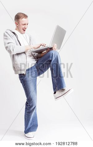 Youth Lifestyle Concepts and Ideas. Portrait of Happy Caucasian Man in Casual Clothing Posing with Laptop on Hands Against White Background. Vertical Image