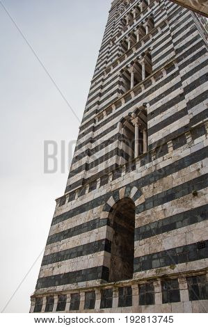 Italy Siena - December 26 2016: the view of bell tower of Duomo di Siena. The view of Romanesque stylistic patterns on Campanile on December 26 2016 in Siena Tuscany Italy.