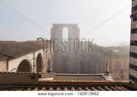 Italy Siena - December 26 2016: the view of the tiled roofs and incomplete facade of the planned Duomo nuovo in fog. Facciatone on December 26 2016 in Siena Tuscany Italy.