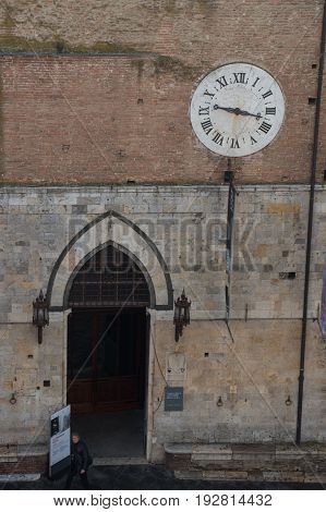 Italy Siena - December 26 2016: the view of Santa Maria della Scala entrance and ancient clock 1643 AD with only hours hand on December 26 2016 in Siena Tuscany Italy.