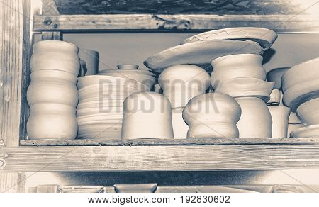 Bright pottery. Many white, not painted clay pottery standing on wooden shelves