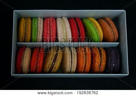 Colorful french  macaroons in a gift box on a black background. Closeup. Top view.
