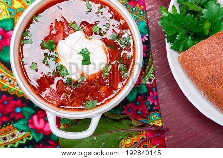 Ukrainian traditional borsch. Russian vegetarian red soup  in white bowl on red wooden background. Top view.  Borscht, borshch with beet