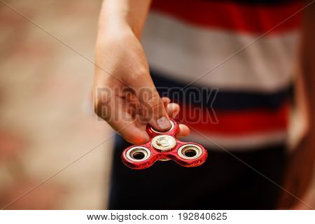 Schoolboy holds a spinner fidget in his hands. Trendy and popular toy for children and adult