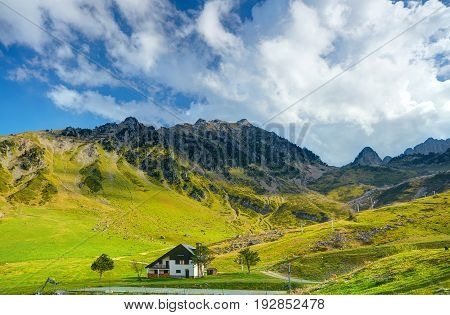 View on Pyrennes mountains green hils and little white house in a valley. Romantic cloudy blue sky. White house in mountains. Stone rocks. France holidays vacations famous best tours trip travels