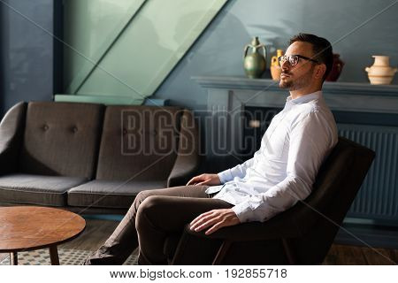 Portait of young handsome businessman in glasses sitting