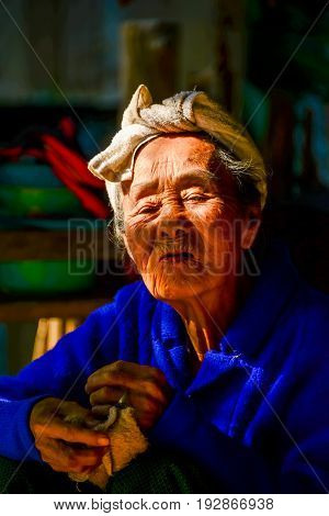 CHIANGMAI THAILAND - JANUARY 24 2015: Indigenous senior woman in light and shadow looking to visitors in Mae Chaem of Chiangmai Thailand