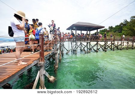 KOTA KINABALU MALAYSIA- 24 JUN 2017: Tourists walk on Sapi Island footbridge in Malaysia. Sapi Island is a favorite destination of tourists.