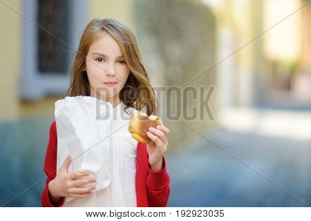 Adorable Little Girl Eating Fresh Baked Bun On Warm And Sunny Summer Day In Toscolano-maderno Town