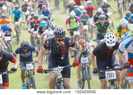 STOCKHOLM SWEDEN - JUNE 11 2017: Lots of mountain bike cyclist struggling in a steep uphill at Lida Loop Mountain bike Race. June 11 2017 in Stockholm Sweden