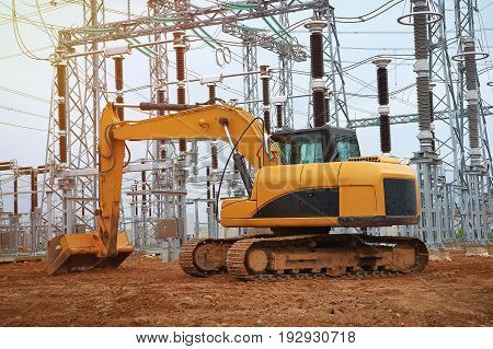 Excavator on industrial construction of energy facility. Excavator on background of industrial electrical equipment of power plant. Construction machinery and heavy machinery