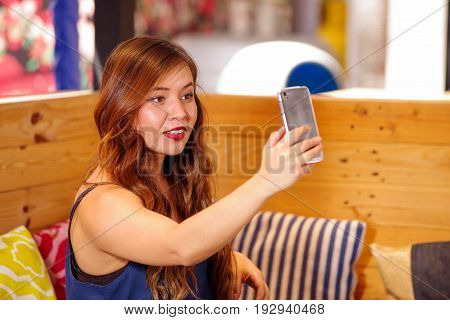 Smiling beautiful woman spending time in a bar, is taking a selfie herself.