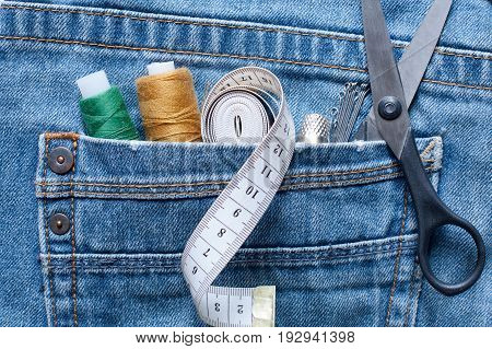 Seam Ripper Thread Centimeter Tape Thimble Pins Scissors In Pocket Of Blue Jeans On White Background Close Up.