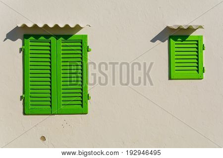 Closed old green window on white destoyed wall. Vintage house and typical mediterranean dwelling
