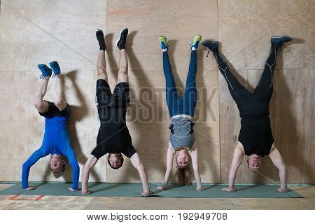 People Handstand push-up workout at gym, pushups updide down near the wall