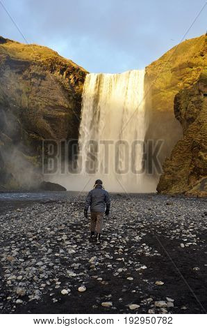 Man walking up to waterfall in iceland
