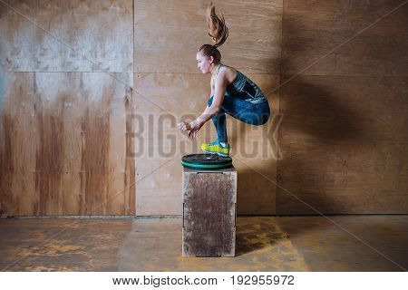 Sporty fit yuong woman jumping over high box during fitness workout, Side view