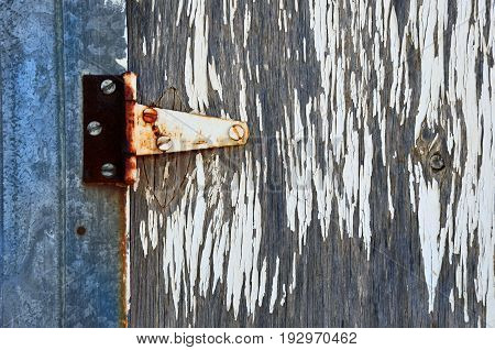 An abstract image of an old rusted door hinge with white peeling paint.