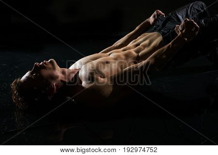 Athletic young man in jeans and with naked torso taking shower studio portrait