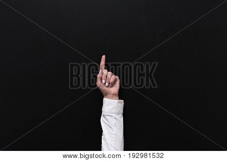 cropped shot of businesswoman pointing up with finger isolated on black
