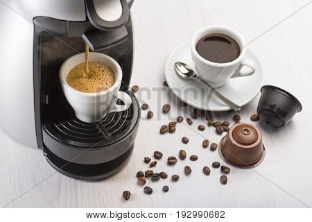coffee machine in operation on table with coffee cup and coffee dispenser.