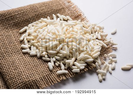 Puffed rice also known as Murmura or Murmure in hindi served in a colourful ceramic bowl or plate or over gunny bag, isolated, selective focus