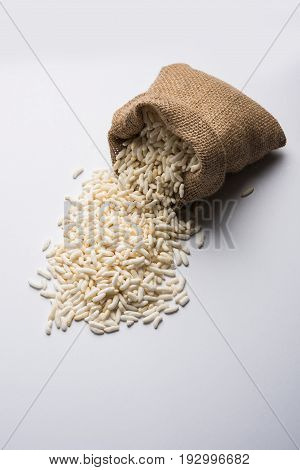 Puffed rice also known as Murmura or Murmure in hindi served in a colourful ceramic bowl or plate or over gunny bag, isolated, selective focus