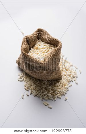 Puffed rice also known as Murmura or Murmure in hindi served in a colourful ceramic bowl or plate or over gunny bag, isolated, selective focus