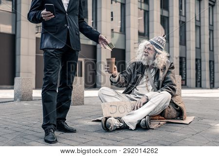 Smiling Grey-haired Dirty Jobless Man Sitting On Ground