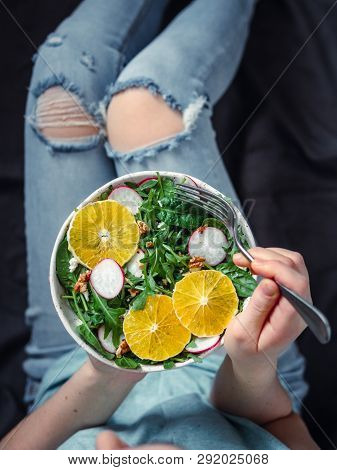 Woman In Jeans At Bed, Holding Vegan Salad Bowl With Oranges, Spinach, Arugula, Radish, Nut.top View