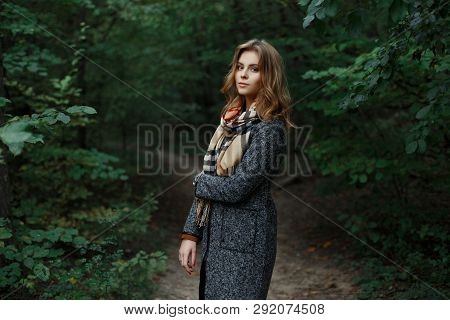 Pretty Attractive European Young Woman In A Fashionable Checkered Scarf In A Chic Gray Coat Walks In