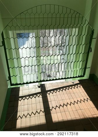 Window Behind The Figured Grate In Form Of An Arch And Cells In Form Of Elongated Cells. The Sun Shi