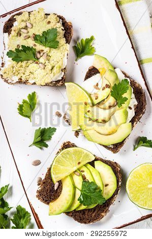 Sandwiches With Avocado And Cream Cheese With Grain Bread. White Wooden Background, Top View.