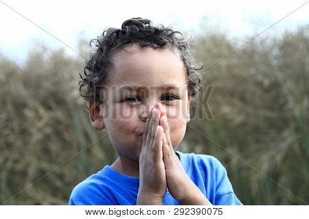 Little Boy Praying To God With Hands Held Together And Head Up High With Eyes Open On White Backgrou