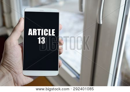 A Man Is Holding A Smartphone With Article 13 Inscription