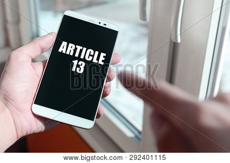 A Man Is Holding A Smartphone With Article 13 Inscription