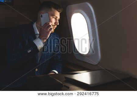 Young Attractive And Successful Businessman Talking On The Phone And Working While Sitting In The Ch