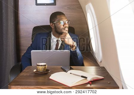 Attractive And Successful African American Businessman With Glasses Working On A Laptop While Sittin