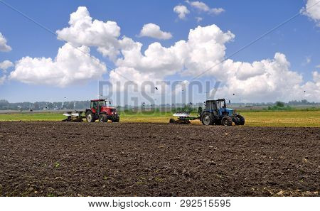 Two Wheeled Tractors Plow The Ground Against The Blue Sky