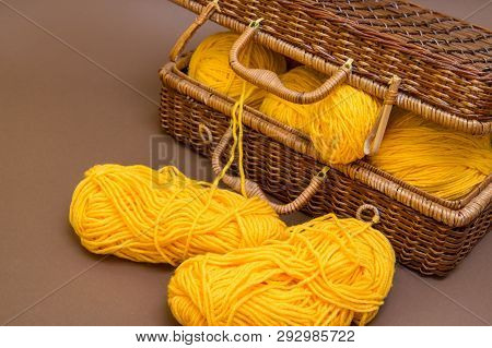 Balls Of Wool For Knitting Yellow In A Wicker Wooden Basket On The Brown Background