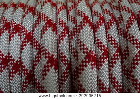 White Rope On A Show-window Of Shop. A Safety And Saving Rope For Climbers. The Rope Is Reeled Up On