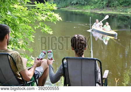 Young Boy And Girl Cheers With Beermix Bewerage Tin Cans Outdoors During Fishing. Beermix Is Product