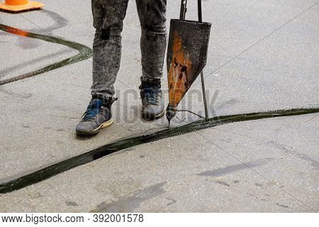 Road Surface Restoration Work In The Worker Performs On Road Patcher Work The Repair Of Cracks By Fi