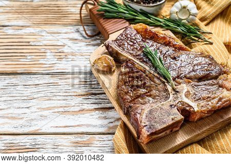 Grilled T Bone Steak On A Chopping Board. Cooked Tbone Beef. White Wooden Background. Top View. Copy