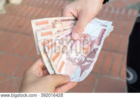 Cropped Shot View Of Someone Giving Or Payment Banknotes Of Laos Kip Money To Other Person. Kip Is T