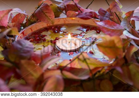 Autumn Candlestick: A Lit Candle In A Bowl Of Water, Rowan Berries And Yellow Maple Leaves Surrounde