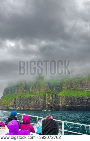 Unrecognizable Tourists Over Boat Observing Impressive Vestmanna Cliffs