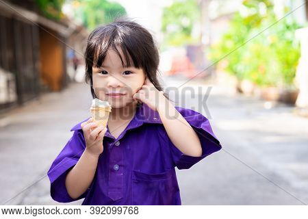 Girl Are Eating Ice Cream Cone On Hot Evening After School. Cute Asian Child With Sweet Smile Lookin