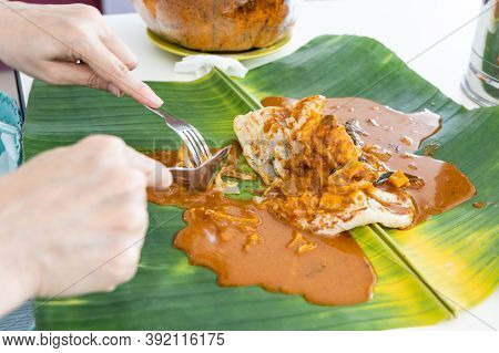 Person Eating Roti Canai Or Paratha Served With Curry Served On Banana Leaf