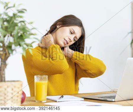 Woman Massaging Neck Pain From Working At Computer For Long Time